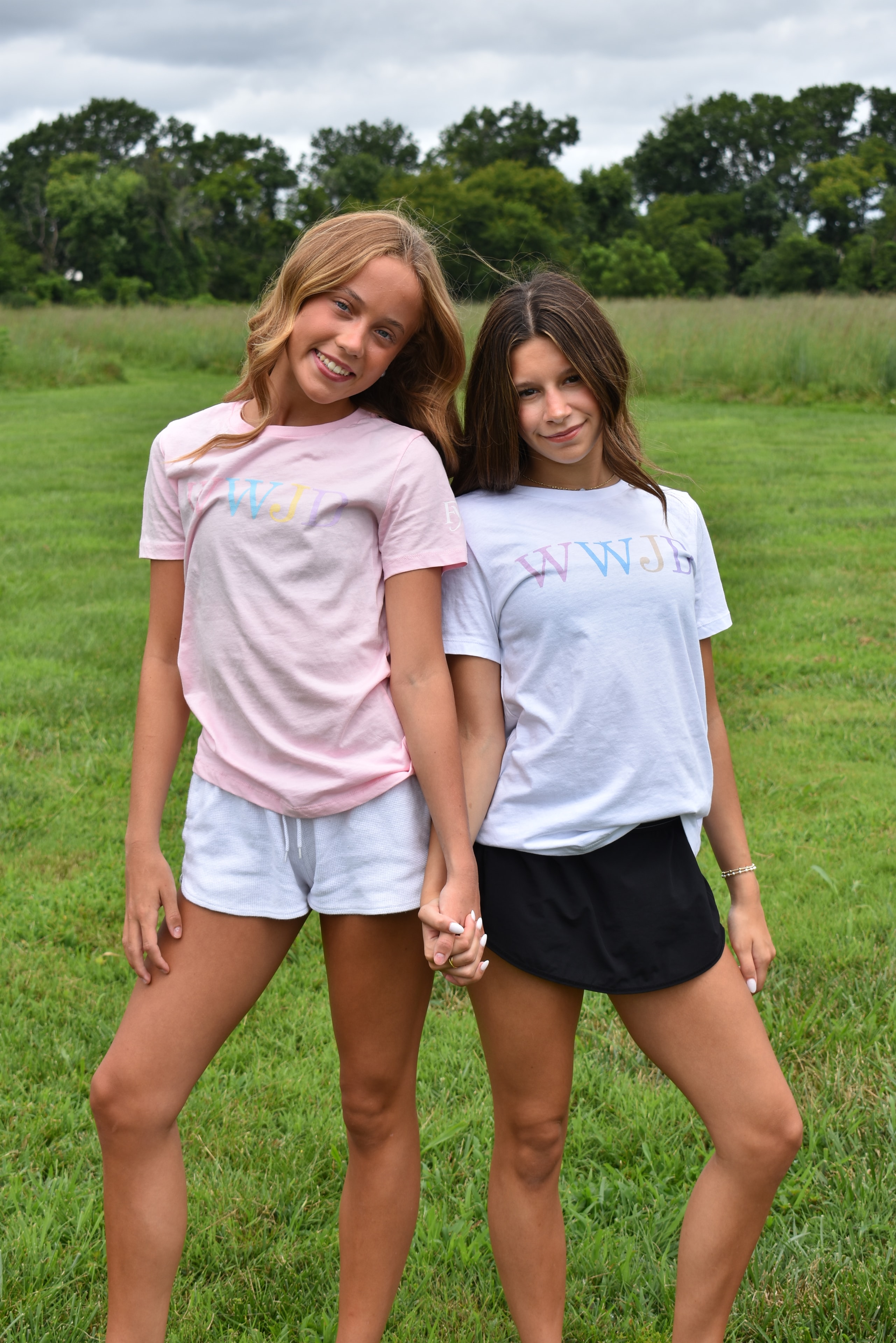 Two girls holding hands in a meadow