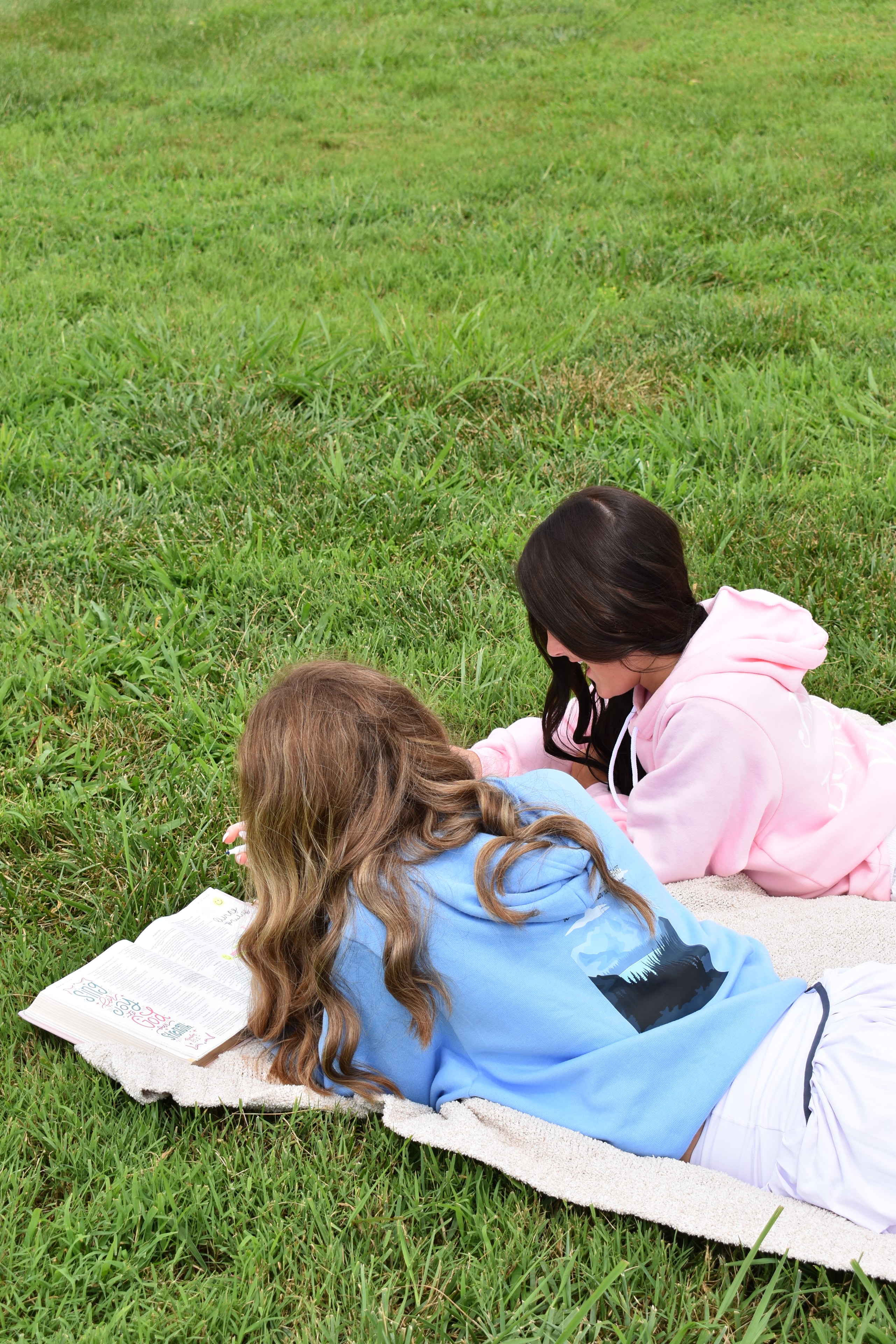 Two girls relaxing on a blanket outdoors