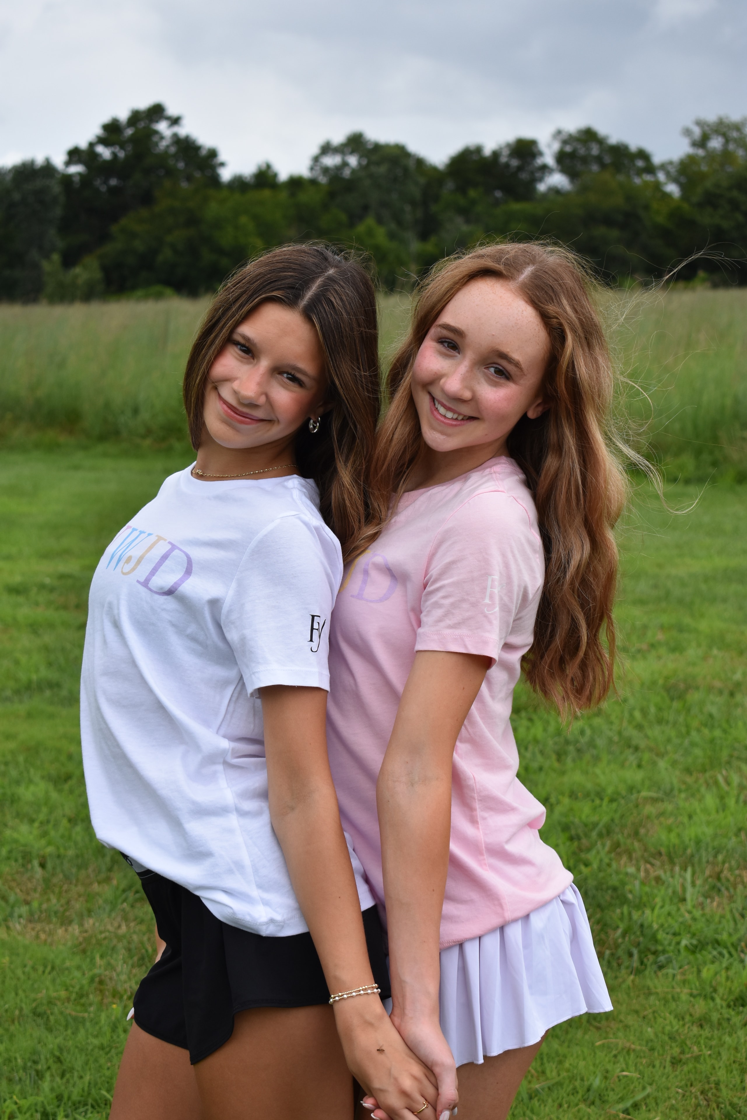 Two teenage girls posing in a green field