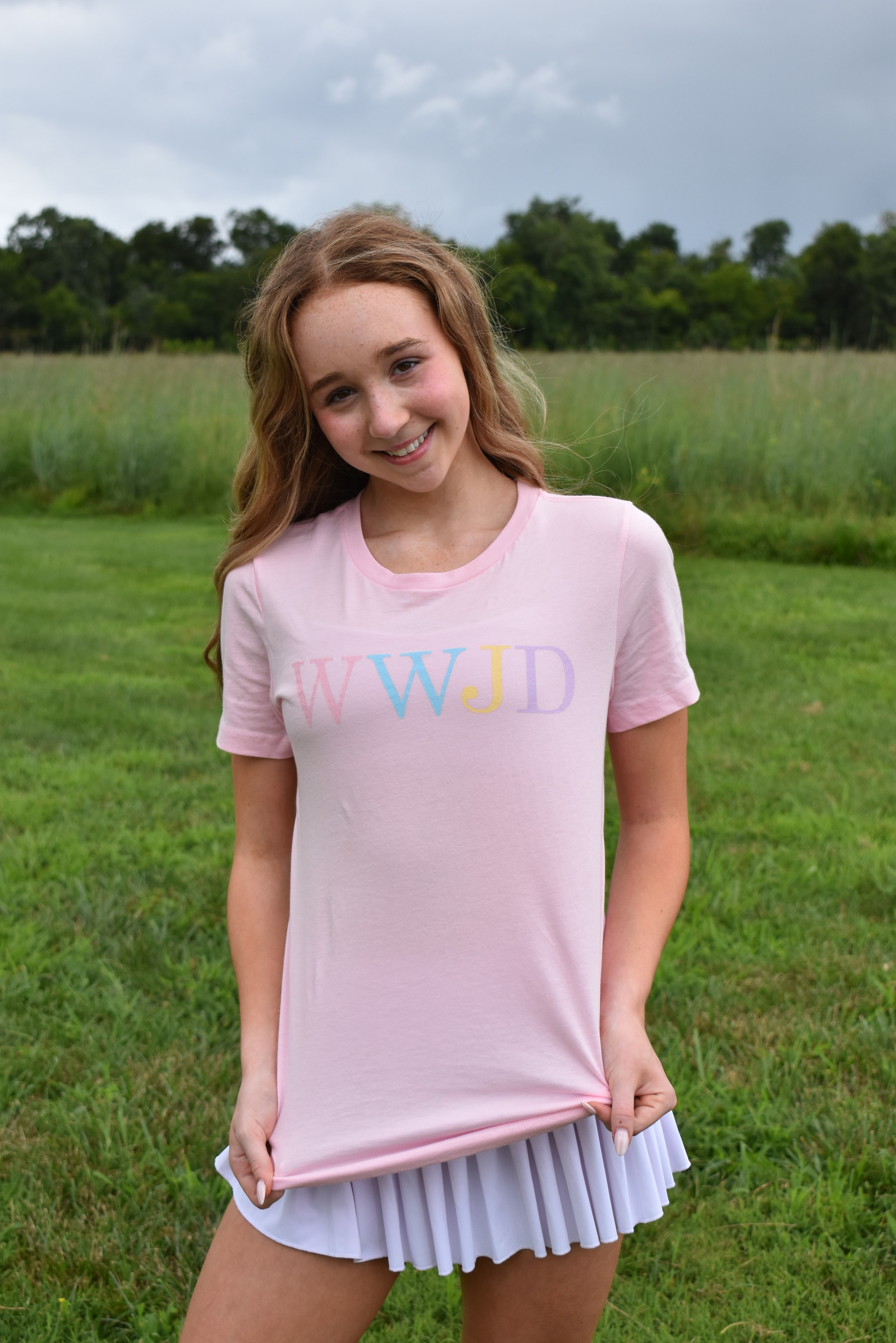 Girl smiling in pink shirt in a meadow
