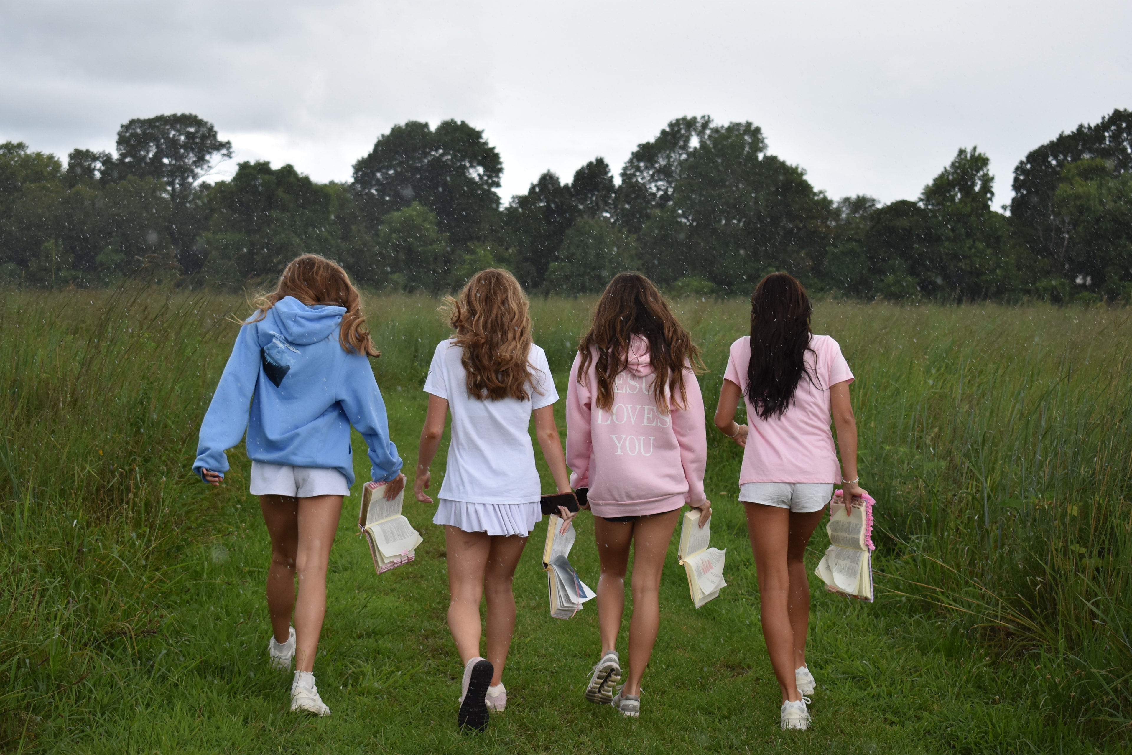 Four girls running through a grassy field